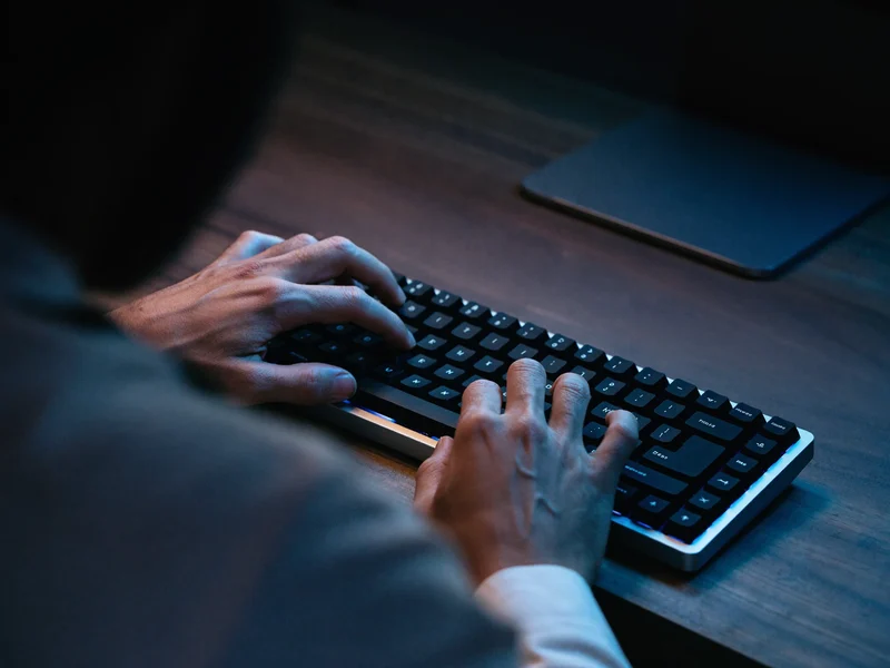 Hände tippen auf einer mechanischen Tastatur bei gedämpftem Licht